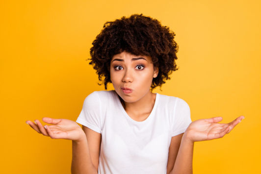 Woman in a white top shrugging shoulders with hands in the air indicating they don't know something