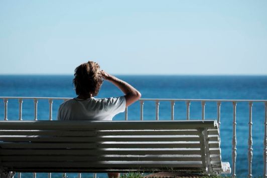 Person sitting on a bench looking out at the ocean