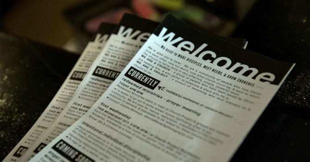 Stack of church bulletins with the word welcome at the top