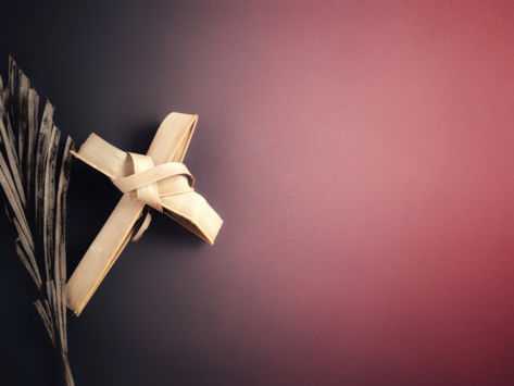 Cross made out of natural materials on a purple / red background